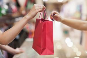 Mulher entrega sacola de compras para cliente: vendas, compras