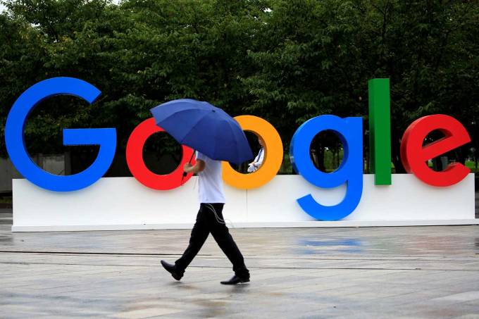 Pessoa caminha em frente ao logo do Google