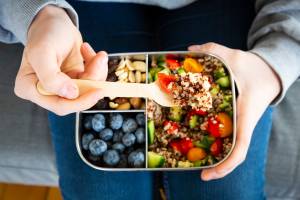 Lunchbox with quinoa salad with tomato and cucumber, blue berry and trail mix