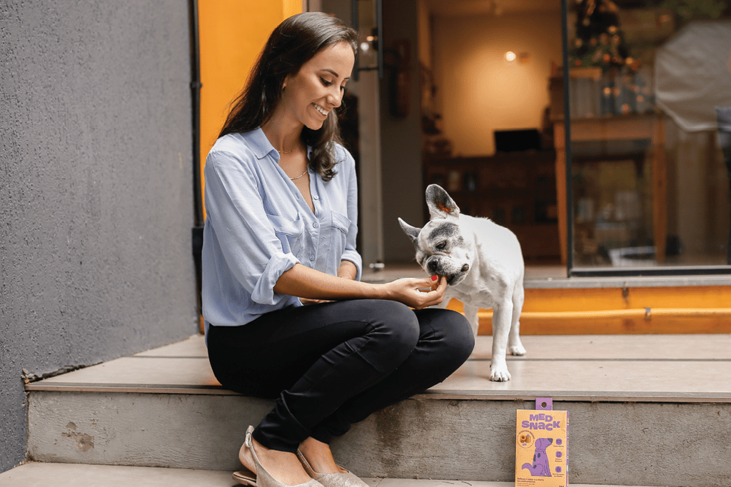 Isadora junto a um cão consumindo seu produto.
