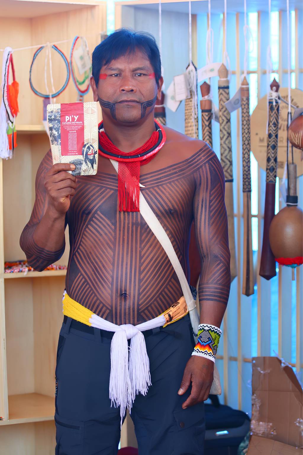 Cooperativa COOBA-Y_divulgação (1) (1) homem indígena, sem camisa e com tataugens ao longo do tronco, segurando um pacote de castanhas, comercializados pela plataforma.