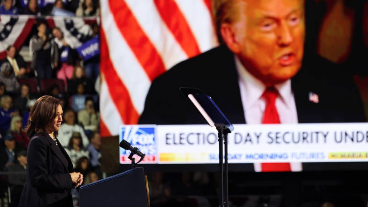 A candidata democrata à presidência Kamala Harris assiste a um vídeo do candidato presidencial republicano Donald Trump em uma tela durante um comício de campanha na Erie Insurance Arena.