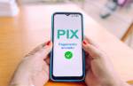 Mãos segurando um smartphone exibindo uma confirmação de pagamento via Pix.