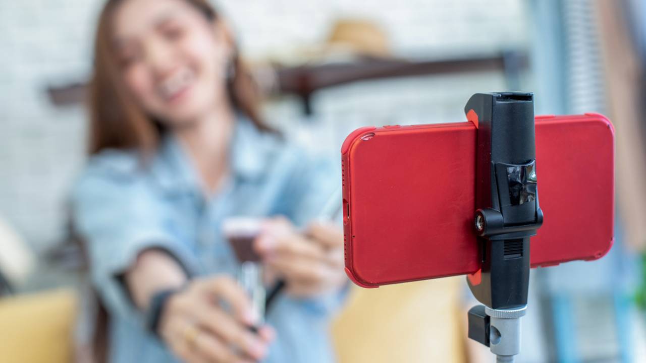 Jovem gravando vlog através do seu celular.