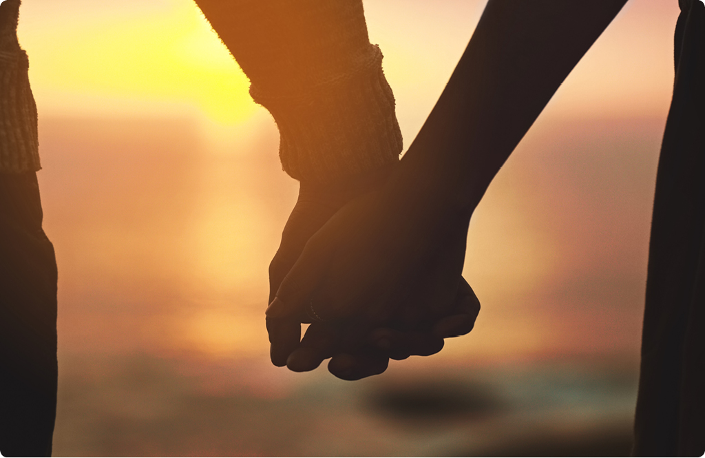 Silhueta de um casal de mãos dadas diante um pôr-do-sol