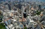 Visão aérea da cidade de São Paulo, composta por muitos prédios altos e tons predominantemente cinzas.